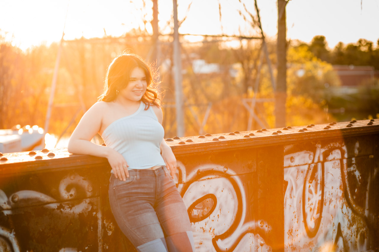 A girl leans back on a metal bridge with graffiti
