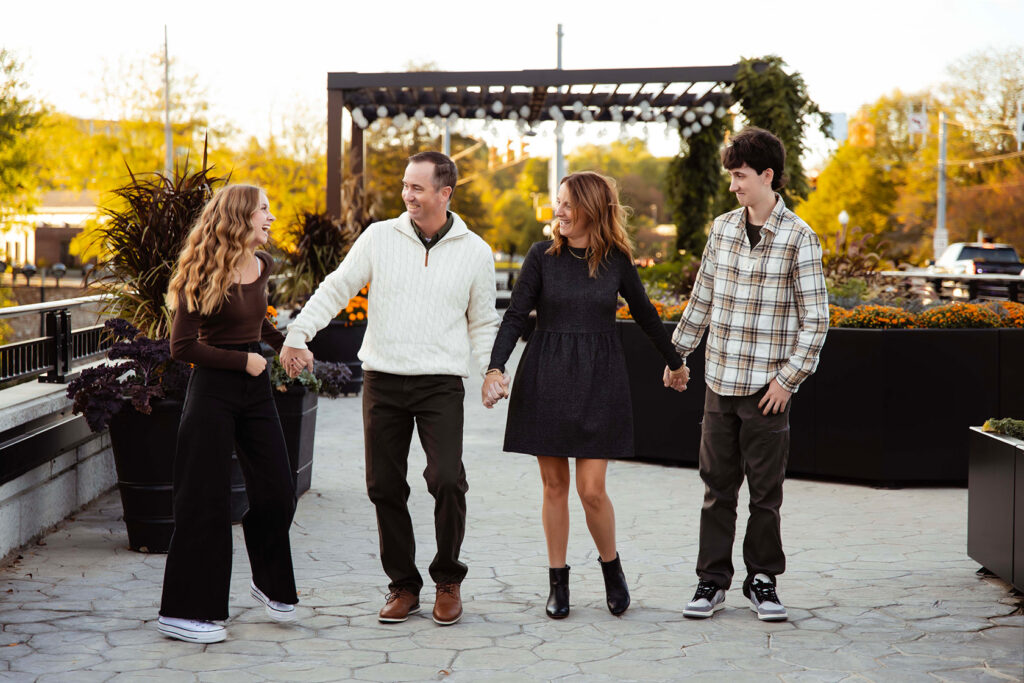 A family of four is holding hands, dancing, and laughing.