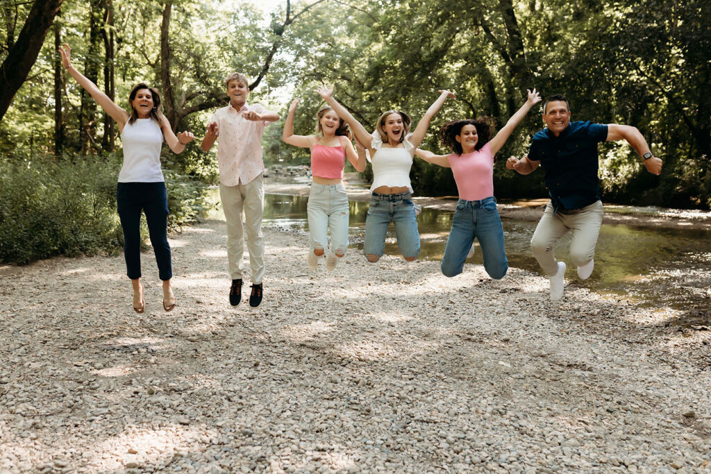A family of six is all in a line, jumping and laughing