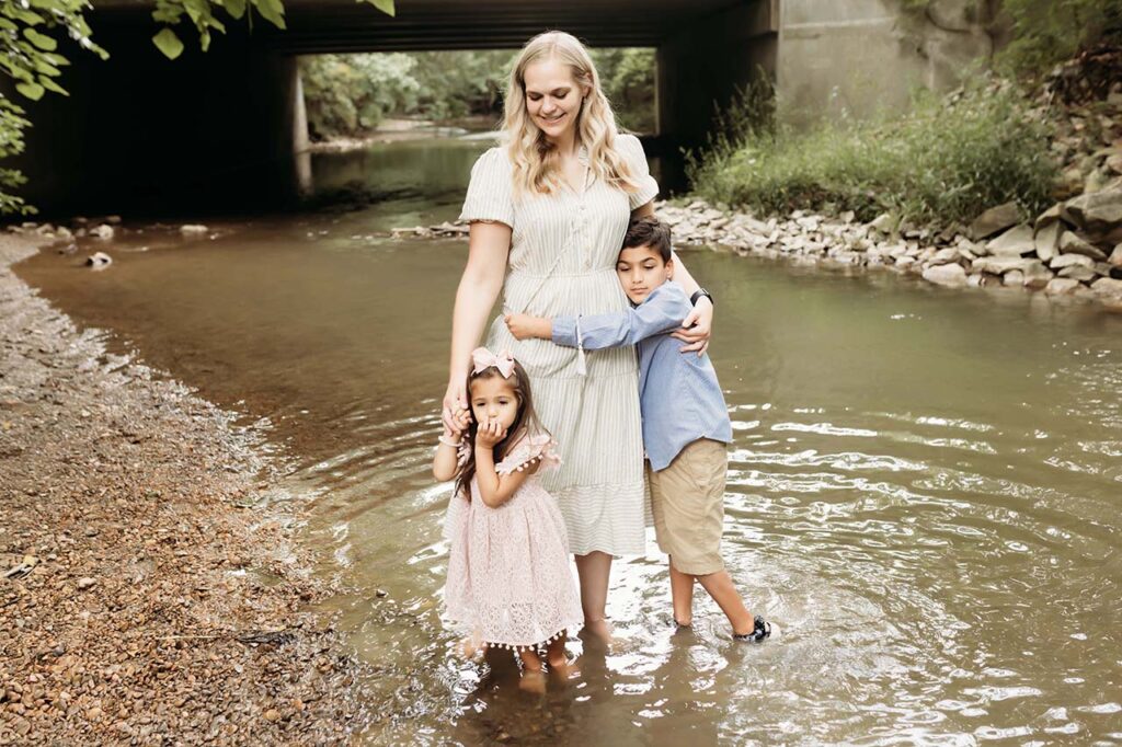 A mom hugging her two kids from behind.