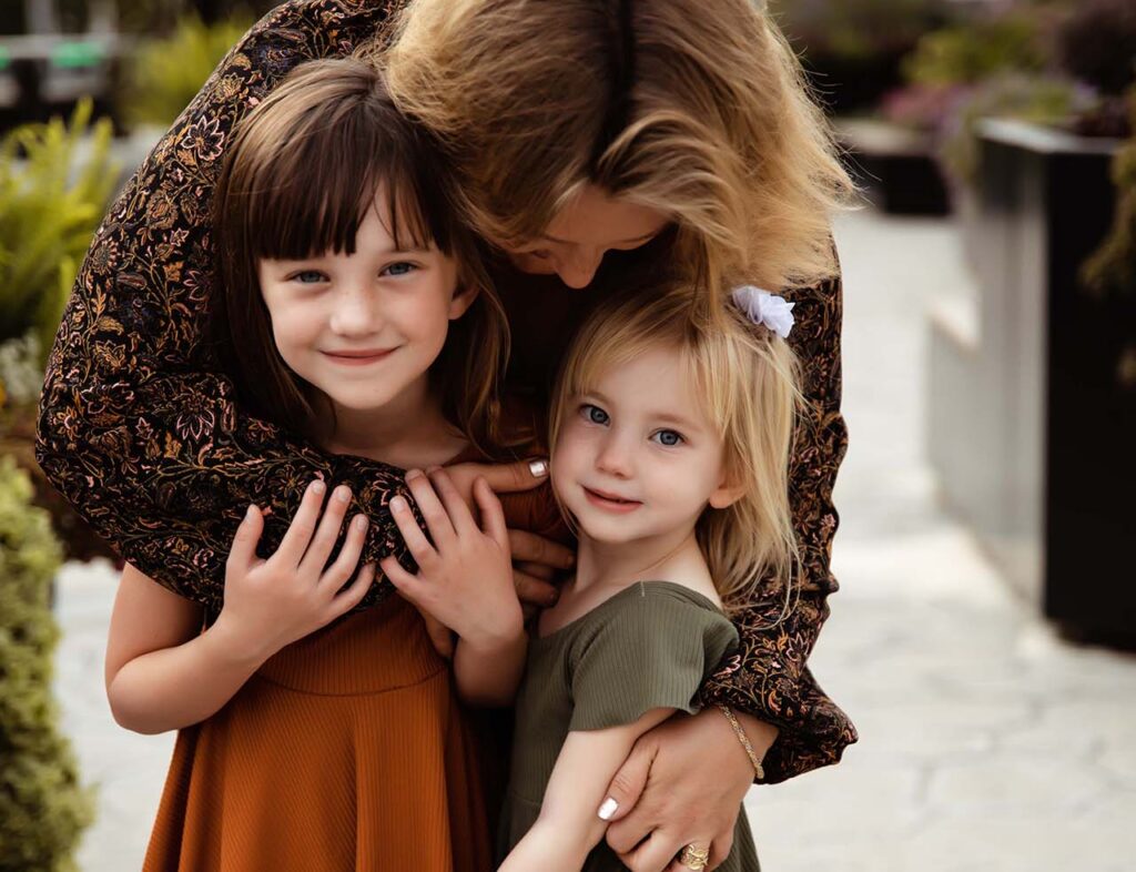Mom hugging her two girls from behind. Indianapolis family photographer