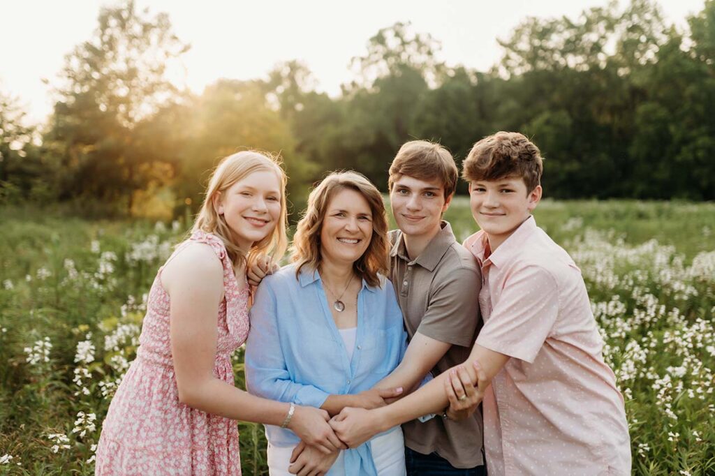 A mom being hugged by her three teenage kids. Indianapolis photographer.
