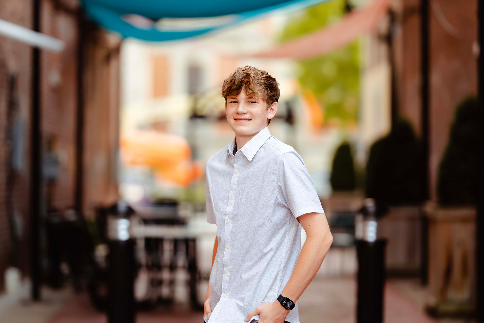 A boy standing in an alley, smiling.