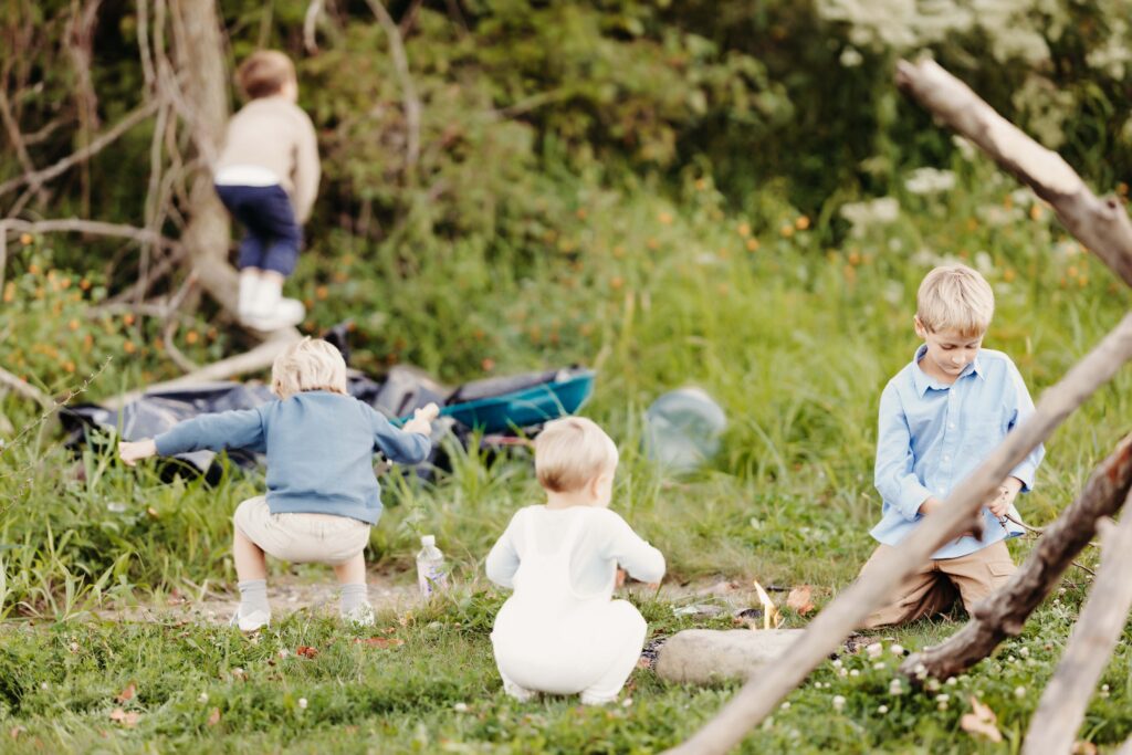 4 little boys playing outside in the dirt and grass with trees and big sticks around. Carmel family photographer. 
