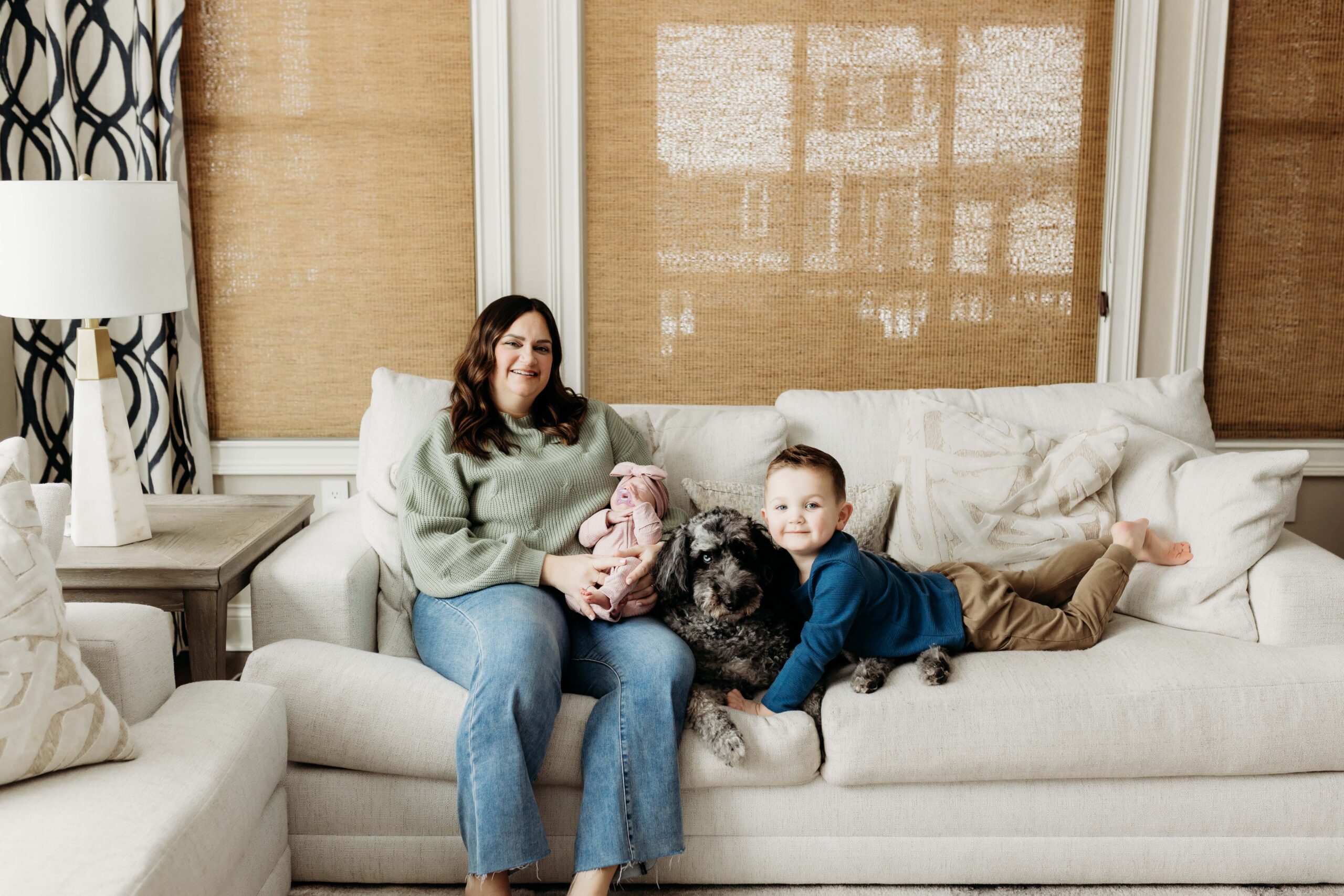 Mom on the couch with her newborn, toddler and dog. Taken by an Indianapolis family photographer.