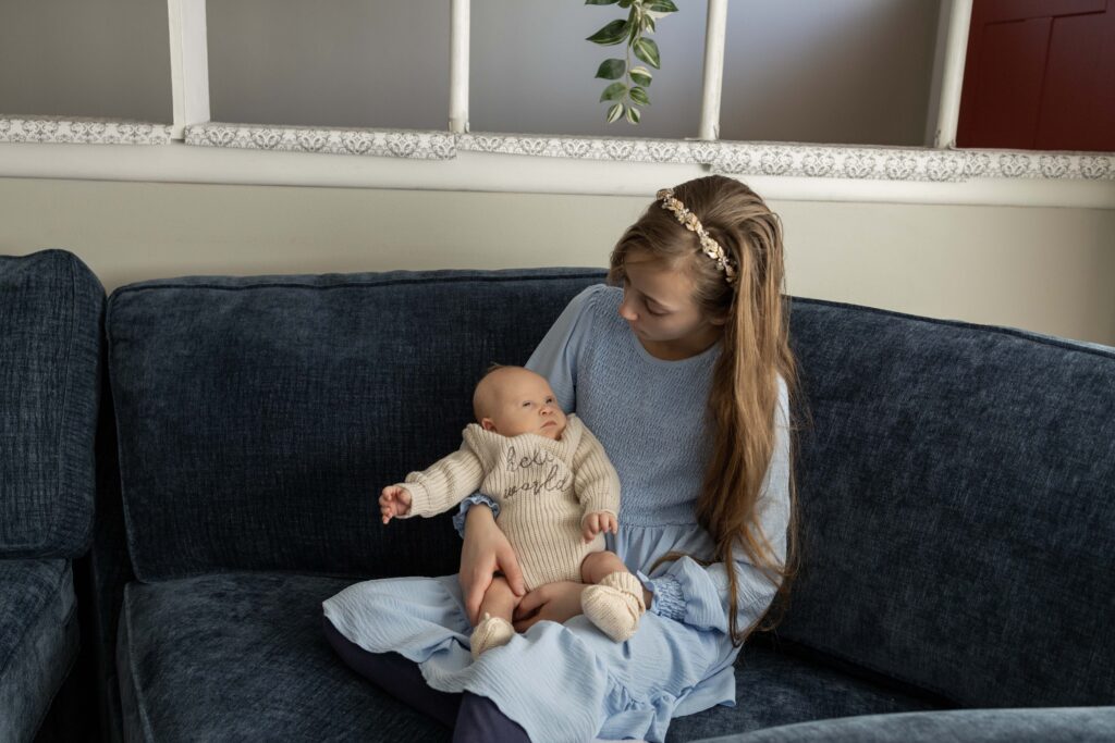 A big sister sits on the couch and snuggles her new baby brother. Indianapolis newborn session.