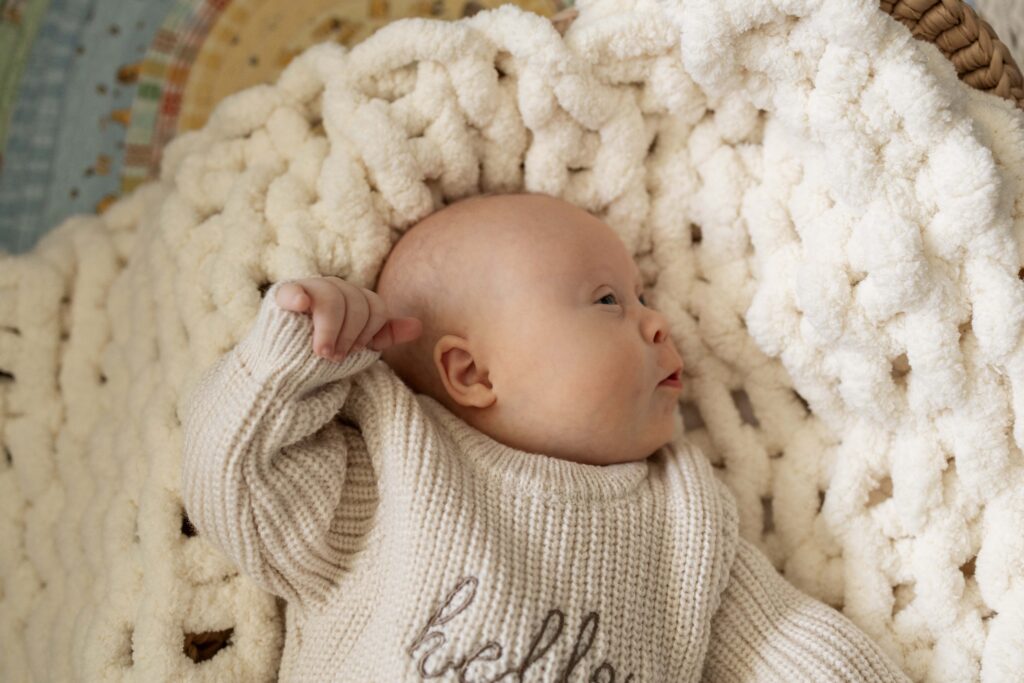 A close-up profile of a newborn baby while hes lying in a baby basket.