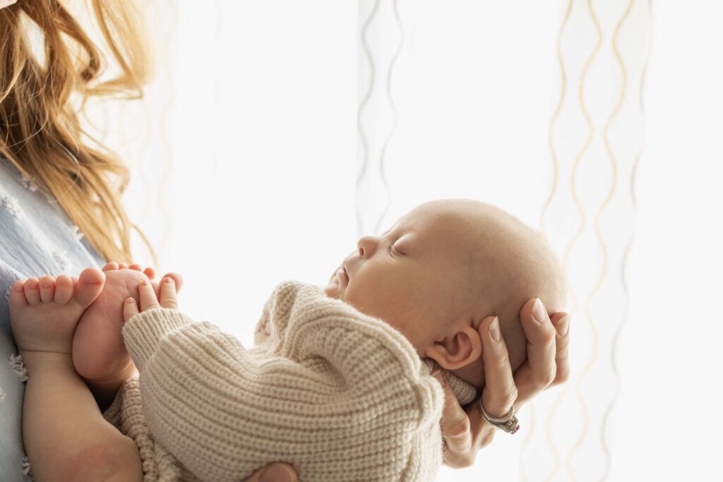 A profile view of a newborn baby with white light behind him.