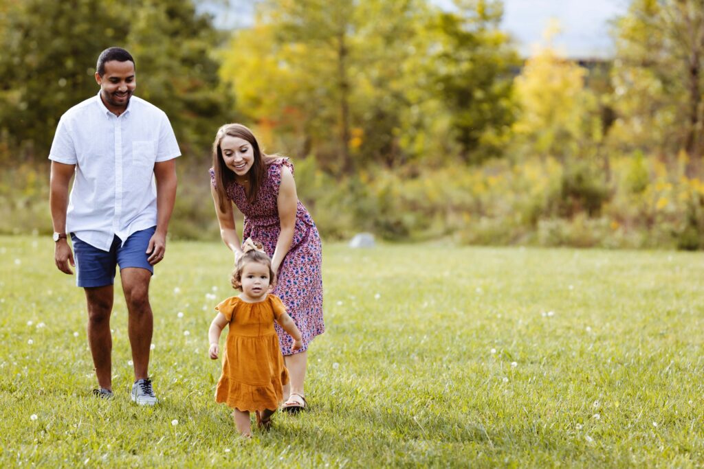 Mom and Dad are in a grassy field with a toddler running around, Westfield family photographer.