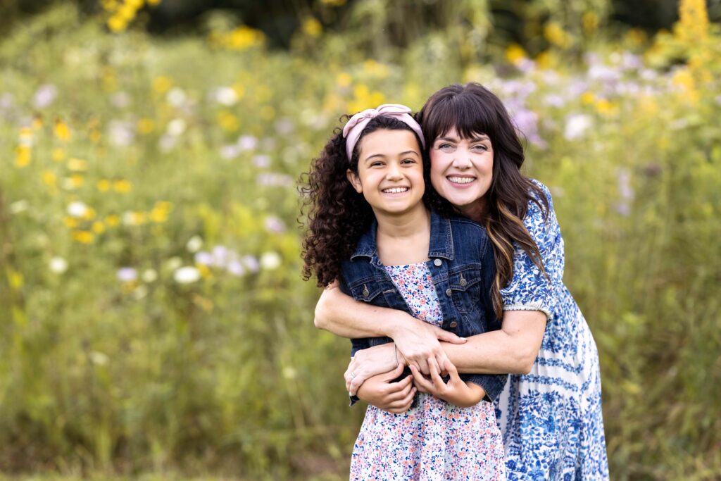 A mom hugging her little girl from behind. They are smiling at the camera. Indianapolis family photographer. 
